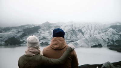 站在冰湖里的年轻夫妇的背影。旅行男女一起探索冰岛