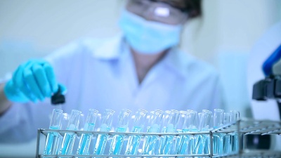 亚洲女科学家在实验室里把固体滴在试管里。医疗保健概念。