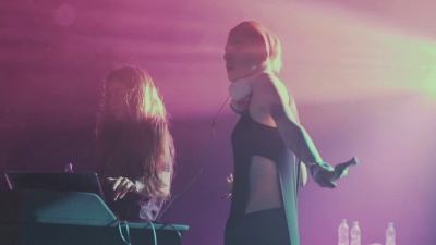 两个漂亮的年轻女子DJ在夜总会的调音台上播放音乐。在无法辨认的人的背景下。慢动作