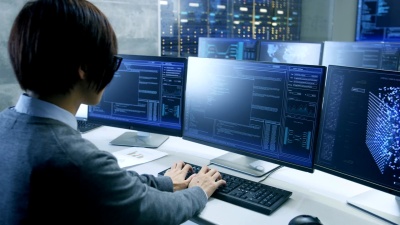 在系统控制室中，技术操作员在其工作站上工作，具有多个显示图形的显示器。可能的发电厂/机场调度员/数据中心/政府监视/空间计划场景。