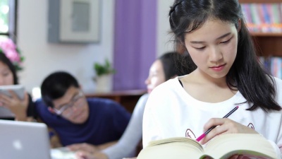 亚裔女大学生在图书馆等待选书