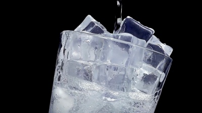 以慢动作将水倒入冰的玻璃杯中