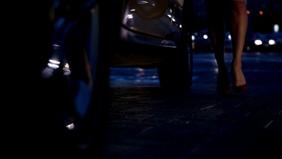 晚上在城市灯光下性感的双腿进入汽车