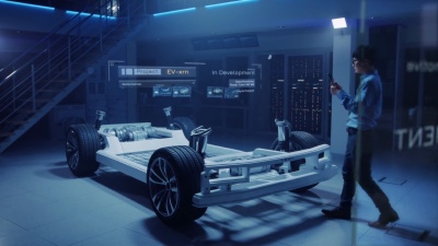 汽车工程师在电动汽车底盘平台上工作，使用平板电脑和增强现实3D软件。创新设施 带车轮的车架成为实体虚拟模型。