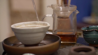 男性双手用绿茶将热水倒入碗中。传统茶道