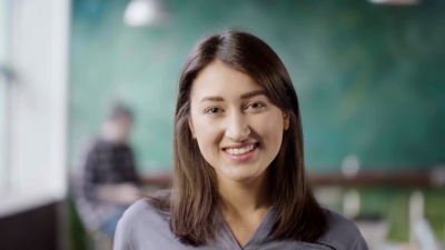 现代办公室里美丽的亚洲女人的肖像。年轻成功的女商人看着摄像机，微笑着