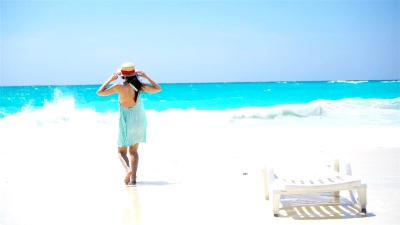 美丽的女人在白色海滩上度过暑假快乐。穿着夏装散步的快乐女孩