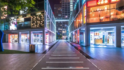 夜晚，现代商业建筑之间的人行道空荡荡的。延时