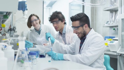 在化学教室实验室工作的多民族积极和兴奋的学生团队。