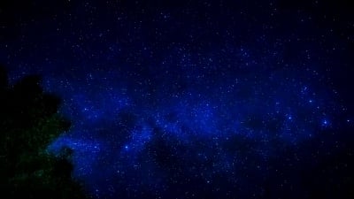 从星星和银河系的美丽运动到蓝色背景和秋天树木前景的时间间隔景观和恒星概念