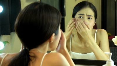年轻的亚洲女孩与痤疮。肖像少女女性照镜子美容，护肤的生活理念