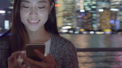 年轻的亚洲女性在现代城市玩手机