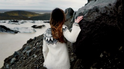 冰岛Vatnajokull冰湖附近，年轻的探险家女子在山上的岩石中行走的背影