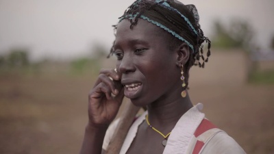 一位年轻的非洲女农民自发地在她的手机上讲话的肖像