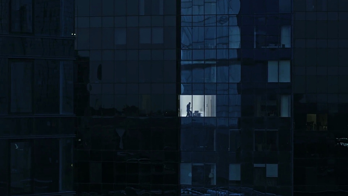 鸟瞰镜头 从室外进入办公大楼，商人使用手机，站在办公窗口旁。美丽的撤退飞行拍摄的金融商业区摩天大楼。