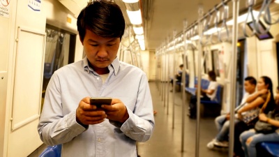亚洲男子在火车上使用智能手机