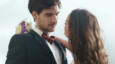 婚礼当天喜气洋洋的新婚夫妇接吻的特写镜头。年轻漂亮的女孩拥抱可爱的帅哥