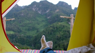 放松女人躺在帐篷里的毯子上交叉腿在露营度假假期的日落时间看山景