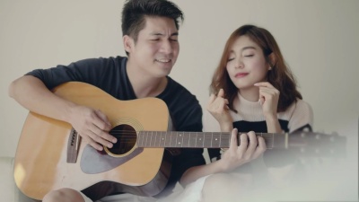 女孩唱歌，而她的男朋友在沙发上弹吉他。