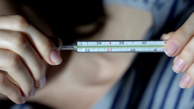 生病的年轻女子手里拿着体温计