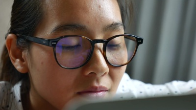 女人看着现代电脑的显示器，把焦点放在眼镜上