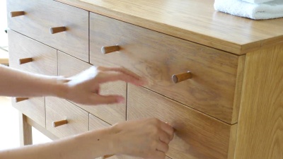   用手拉开柜子抽屉。