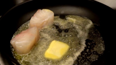 厨师在餐厅厨房里用黄油烤鱼片