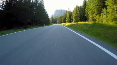 在蜿蜒的道路上行驶，穿过森林，阳光透过树木