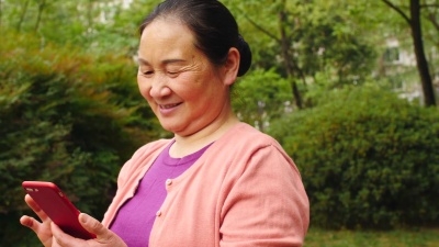 高级亚洲妇女在公园户外使用手机， 