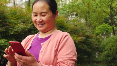 高级亚洲妇女在公园户外使用手机， 