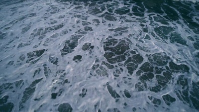 年轻的男子和十几岁的女孩在日落时在海洋中游泳，在海浪中被海浪击中。美国纽约州长岛汉普顿海滩。