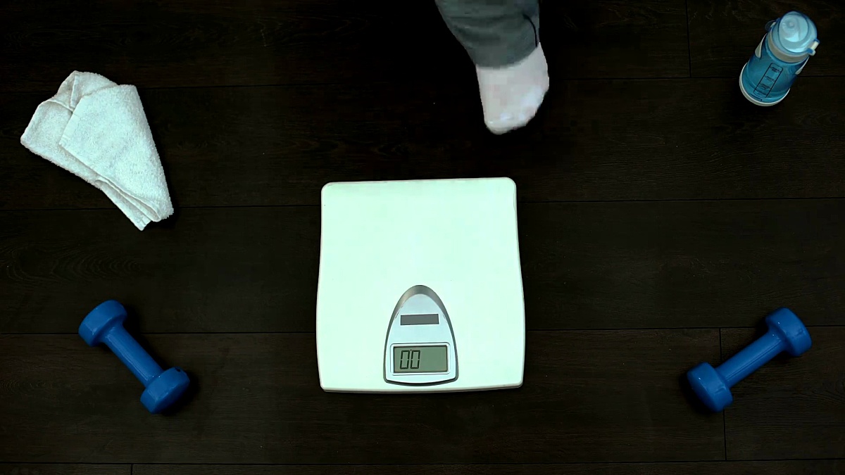 肥胖男子站在健身房秤上，检查体重，减肥训练，节食