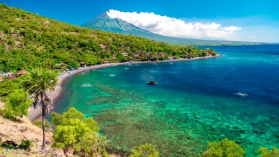 在印度尼西亚巴厘岛的阿贡火山背景上，船只漂浮在亚迈德海湾中。