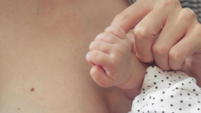 特写镜头，一个新生女婴抱着她母亲的手指。