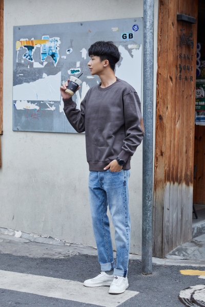 服饰系列实景模特穿着灰色卫衣和蓝色牛仔裤的街头摆拍 