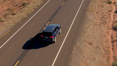 空中特写飞行在沙漠中空旷的道路上行驶的黑色SUV汽车