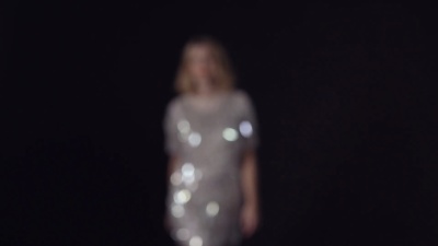 金发女郎，穿着闪闪发光的衣服，走向镜头，进入焦点