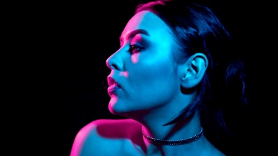 艳丽的深色女人在霓虹灯下抽电子烟