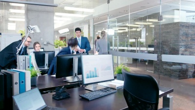 大公司办公室工作日的延时。不同的有才华的商务人员团队在他们的办公桌上工作，开会，讨论。