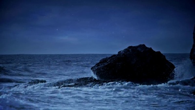 夜间海景，海浪撞击岩石。
