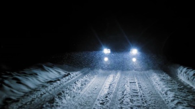 夜里在下雪的雪路上行驶的汽车