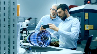 两位工程师在手机上使用增强现实全息投影3D模型的发动机涡轮原型。虚拟混合现实应用程序的开发。