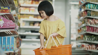 泰国小女孩的注意力集中在超市里挑选和购买一些食物