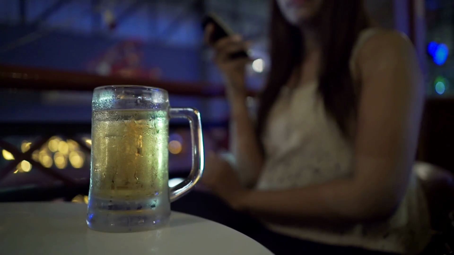 女性喝啤酒和使用智能手机