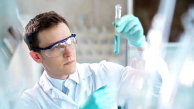年轻的科学家在实验室检查试管。男人戴护目镜