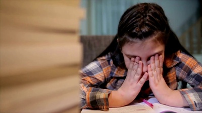 疲惫的女学生在书桌上堆着一堆书学习