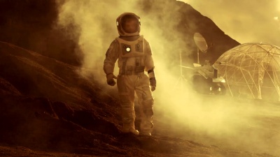 穿着太空服的宇航员在红色星球/火星上行走。在背景中，他的基地与罗孚停在一起，炽热的红色日光照耀着。
