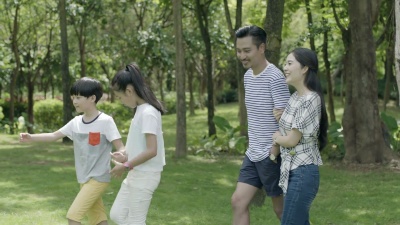 亚洲家庭四口之家在阳光灿烂的夏天在公园里慢动作散步和欢笑