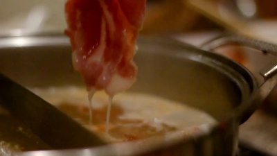用筷子把滑肉放进火锅里