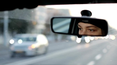 这个女孩正在开车。女性眼睛在汽车后视镜中的反射。